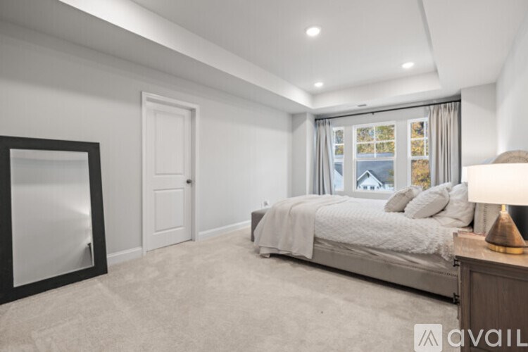 A bedroom with a large bed and a window with curtains.
