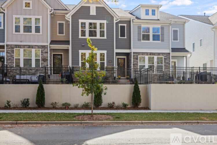 A row of houses with a tree in front of the grey house.