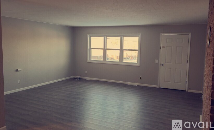 A room with wooden flooring and a window letting in light.