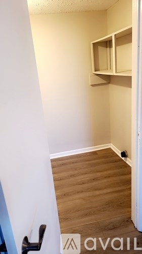 A room with a door and a shelf on the wall.