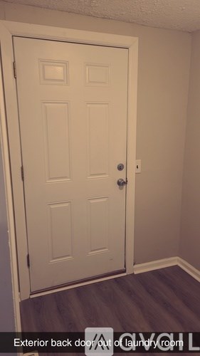 A white door with a handle is in a room with a wooden floor.