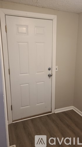 A white door with a silver handle is in a room with wood flooring.