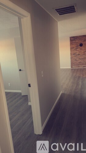 A hallway with a brick wall and a door on the left.