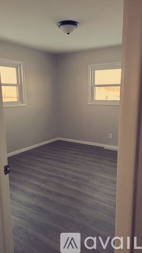 A room with a wooden floor and two windows.