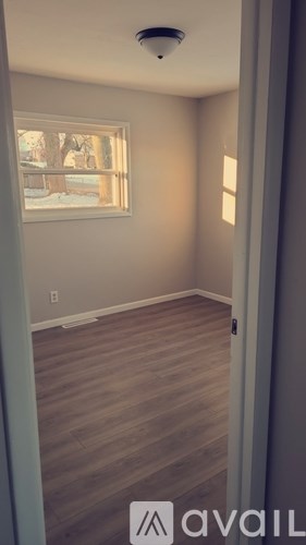 A room with wooden flooring and a window showing a snowy landscape outside.