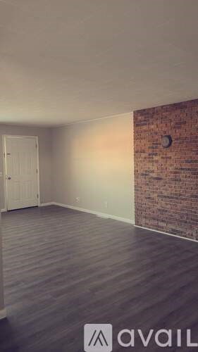 A room with a wooden floor and a brick wall.