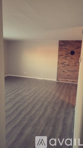 A room with a wooden floor and a brick wall.
