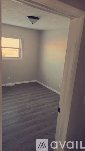 A room with a window and a wooden floor.