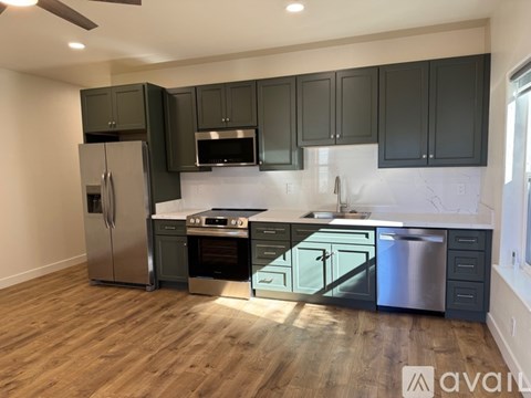 A kitchen with dark green cabinets and stainless steel appliances.