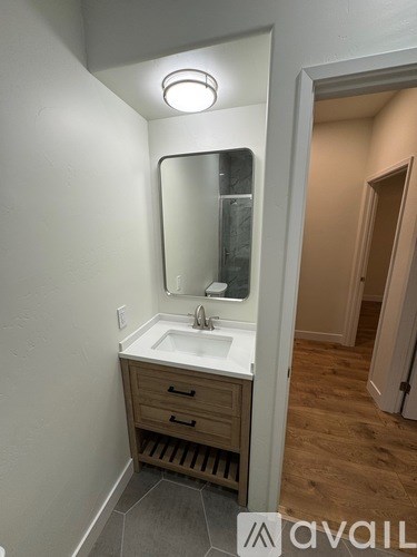A bathroom with a sink, mirror, and wooden drawers.