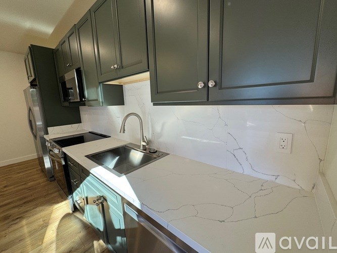 A kitchen with dark green cabinets and a marble countertop.