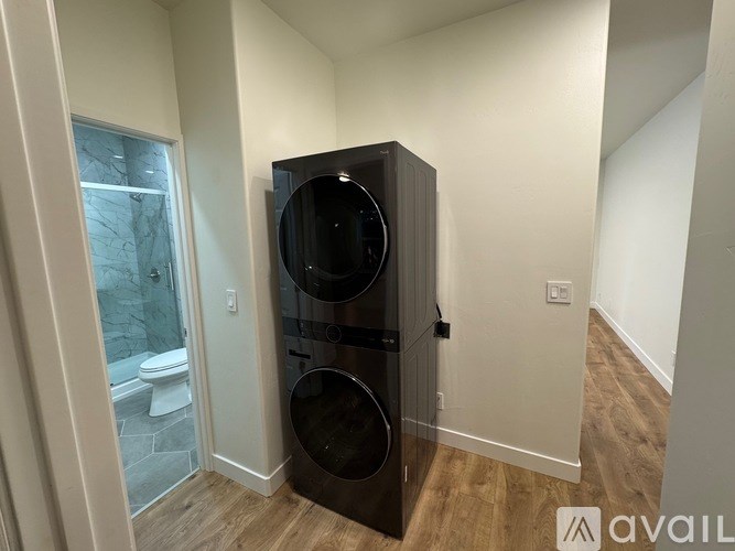 A black fridge in a room with wooden flooring and a glass door.