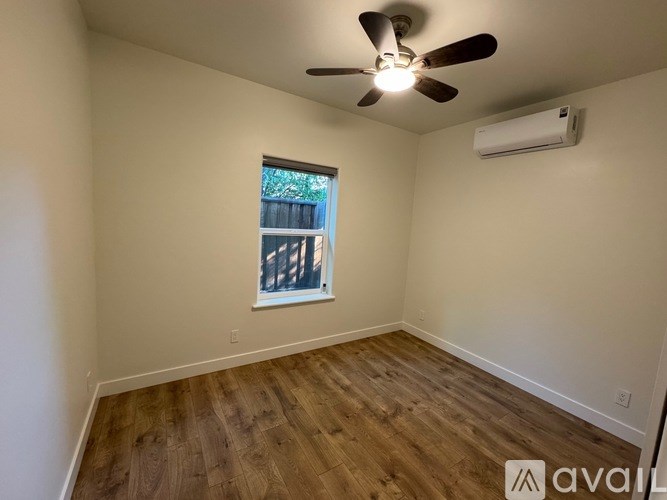 A room with a ceiling fan and wooden flooring.