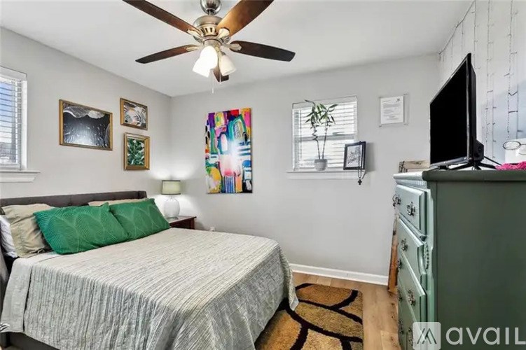 A bedroom with a bed, a dresser, and a ceiling fan.