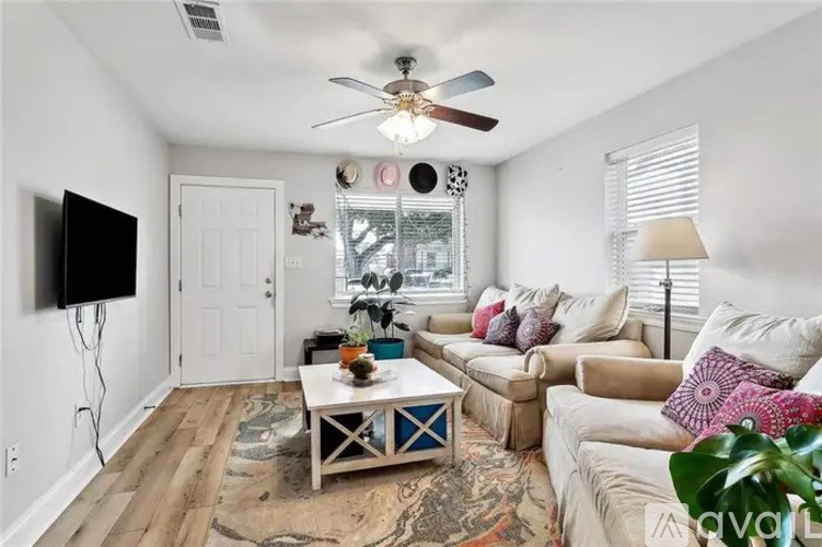 A living room with a white couch, a white coffee table, and a white ceiling fan.