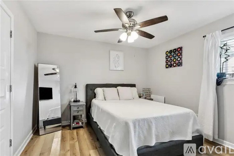 A bedroom with a bed, nightstand, and a ceiling fan.