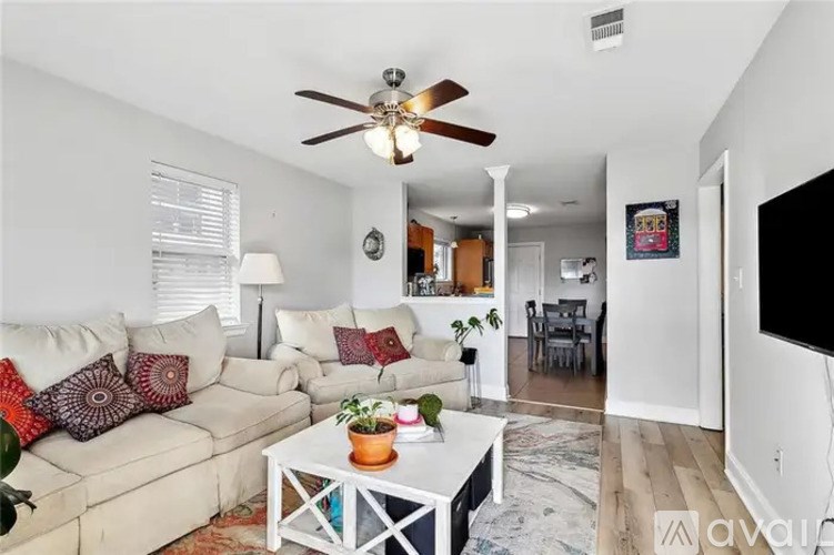A living room with a white couch and a ceiling fan.