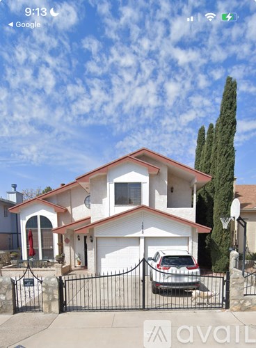 A white house with a black gate and a car parked in front.