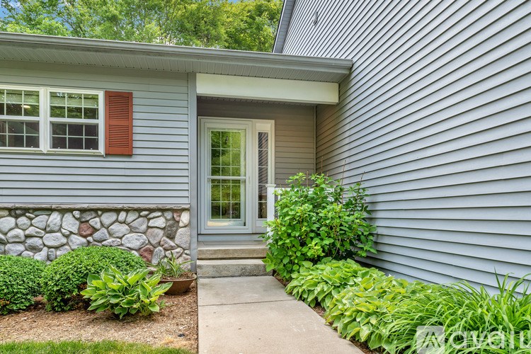 A house with a grey siding and a stone wall.