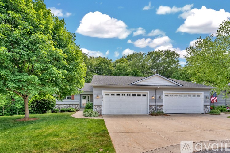 A house with a garage and a tree in front of it.