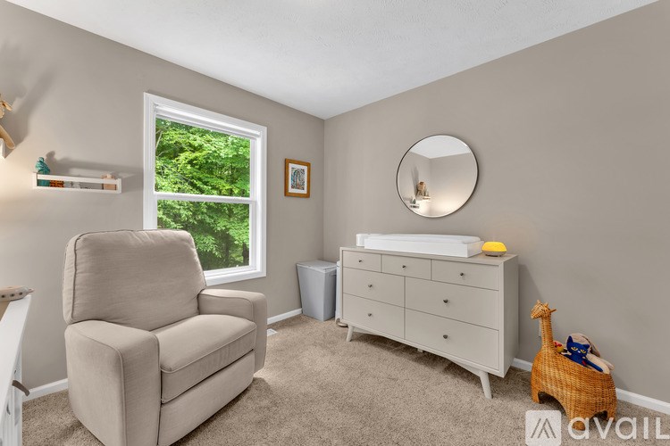 A baby room with a white crib and a beige chair.
