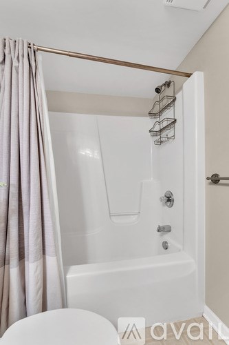 A white bathtub with a shower curtain and a towel rack above it.