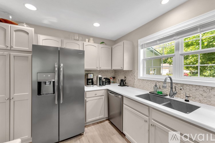 A kitchen with a stainless steel refrigerator and white cabinets.