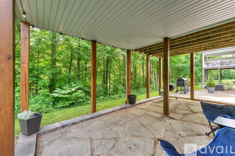 A covered outdoor area with a stone floor and wooden pillars.