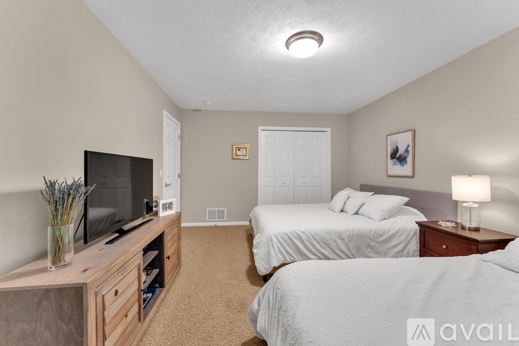 A bedroom with two beds and a television on a wooden stand.