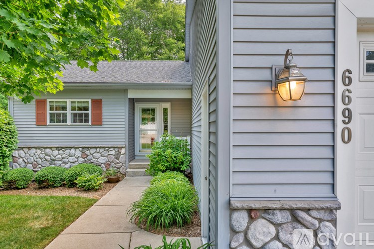 A house numbered 6690 with a white door and a stone wall.