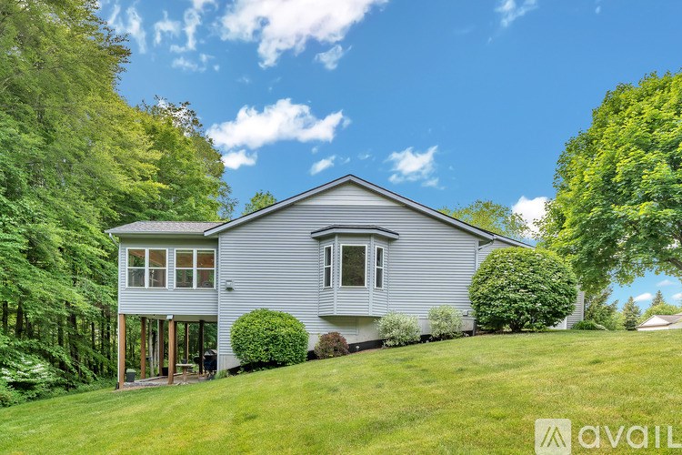 A house with a grey roof and white walls is surrounded by greenery.