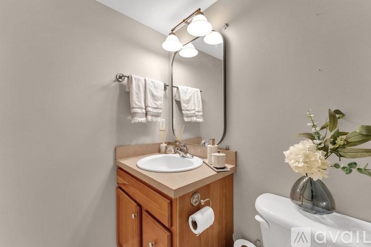 A bathroom with a sink, mirror, and a vase of flowers.