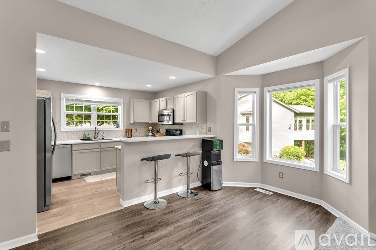 A kitchen with a bar stool and a trash can.