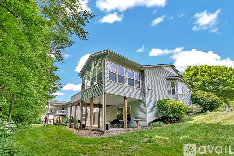 A house with a large front porch is surrounded by greenery.