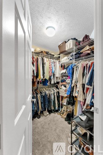 A white closet with clothes hanging on shelves and racks.