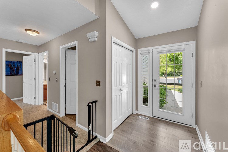 A hallway with white doors and a black railing.