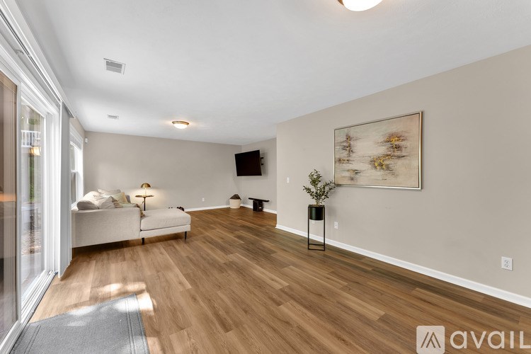 A living room with a white couch and a painting on the wall.