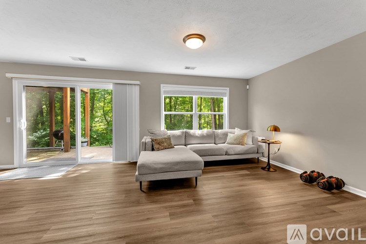 A living room with a white couch and a lamp on a side table.