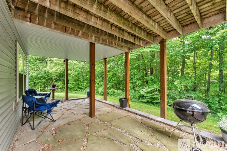 A covered porch with a grill and chairs.