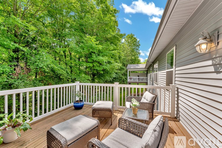 A patio with a white railing and furniture including a couch, chair and ottoman.