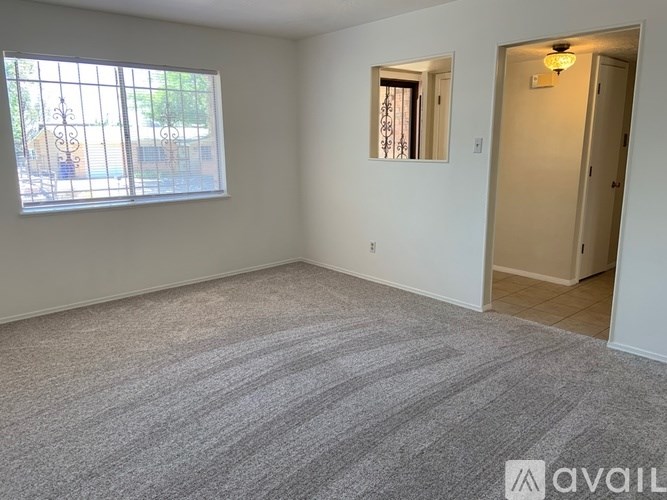 A room with a carpeted floor and a window with blinds.