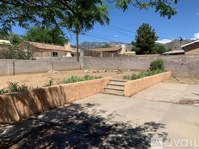 A backyard with a concrete patio and a wooden retaining wall.
