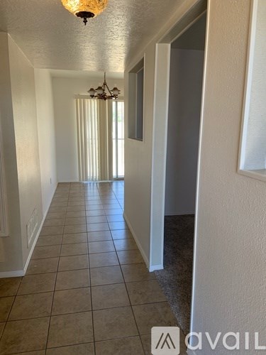 A hallway with a chandelier and a door on the right.