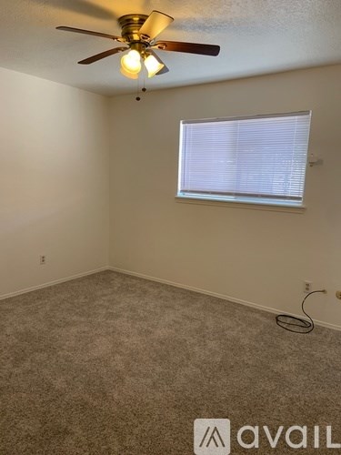 A room with a ceiling fan and a window with blinds.