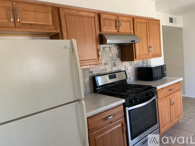 A kitchen with a white fridge, black stove, and wooden cabinets.