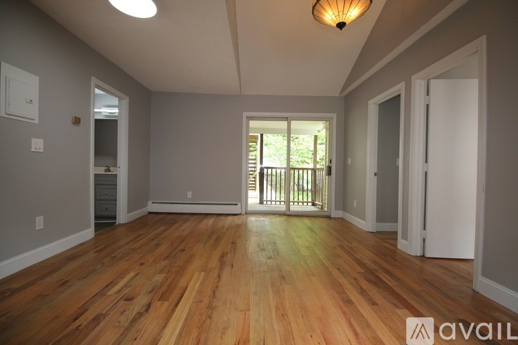 A room with wooden floors and a sliding glass door leading to a balcony.