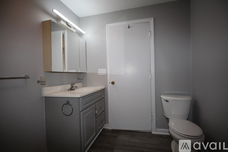 A bathroom with a toilet, sink, and mirror.