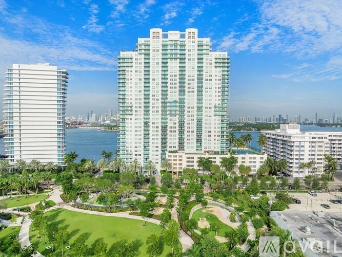 A modern high-rise building with a green lawn in front.