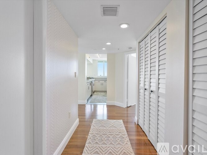 A hallway with a rug on the floor and white walls.