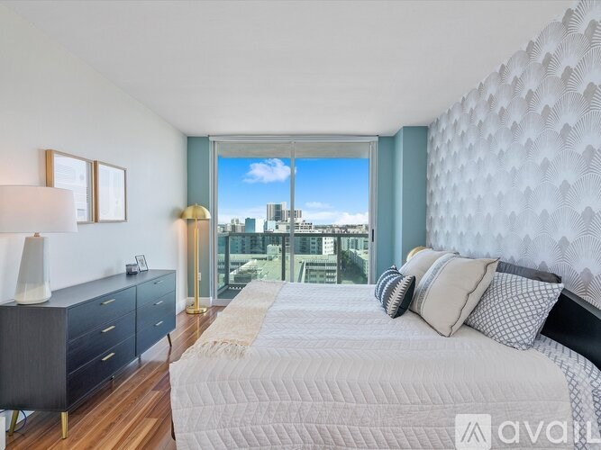 A bedroom with a large bed, a dresser, and a window overlooking a cityscape.